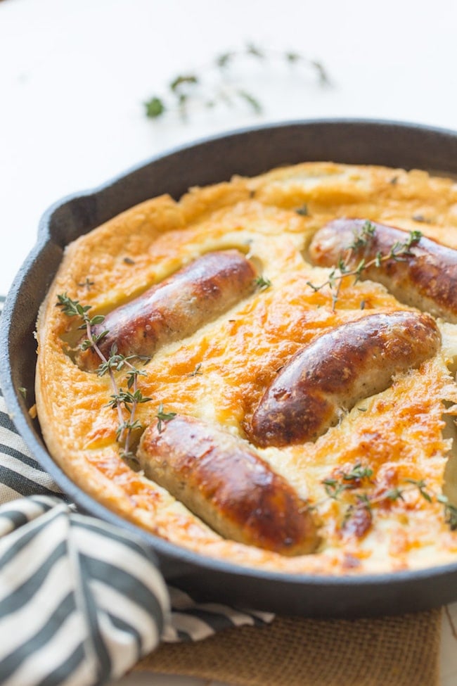 Gluten Free Toad in the Hole in a cast iron skillet with a stripped kitchen towel