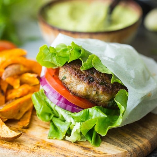 paleo turkey burger in a lettuce wrap with tomato and onion