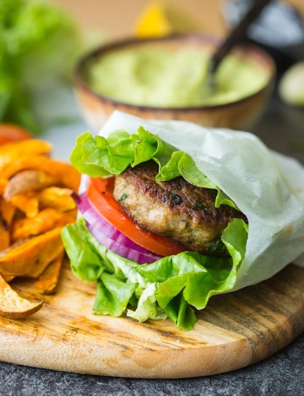 paleo turkey burger in a lettuce wrap with tomato and onion