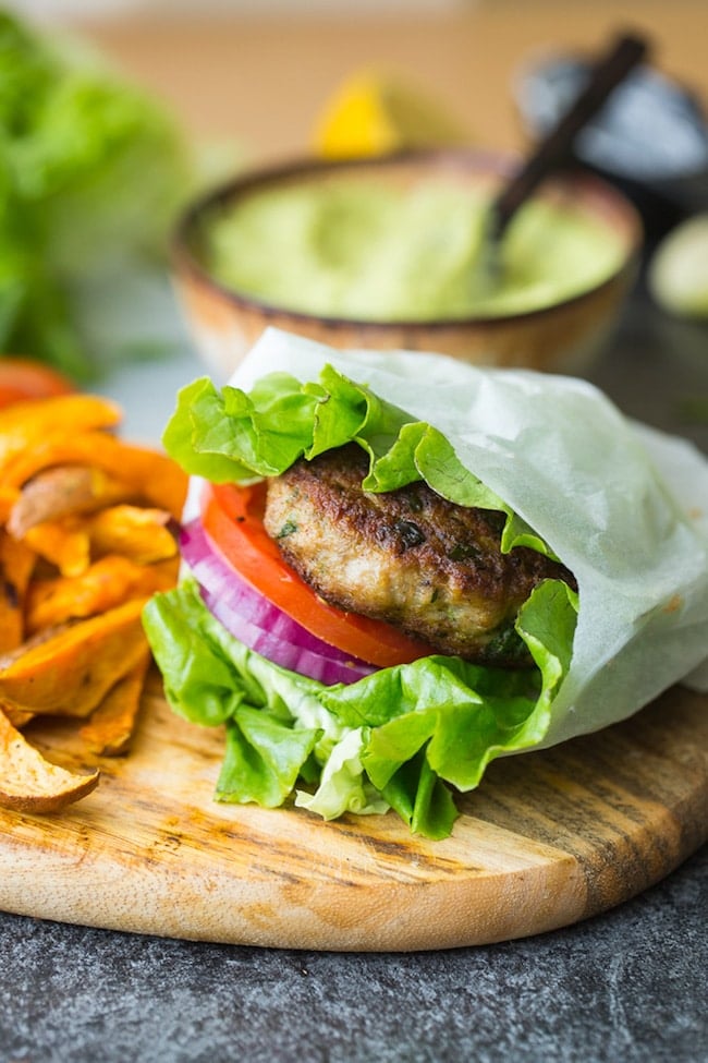 paleo turkey burger in a lettuce wrap with tomato and onion