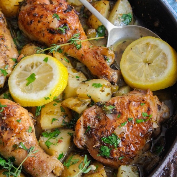 bone-in and skin on chicken thighs in a cast iron skillet with potatoes, lemon slices and thyme