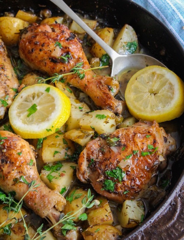 bone-in and skin on chicken thighs in a cast iron skillet with potatoes, lemon slices and thyme