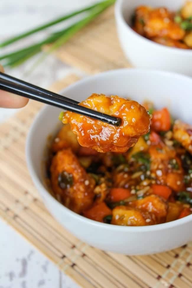 Paleo & Low FODMAP Sweet and Sour Chicken held up with chopsticks 