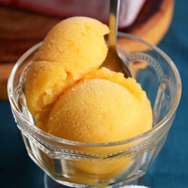 two scoops of pineapple mango sorbet in a serving glass