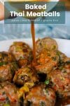 baked paleo thai meatballs stacked in a bowl with a chili sauce pouring over the top