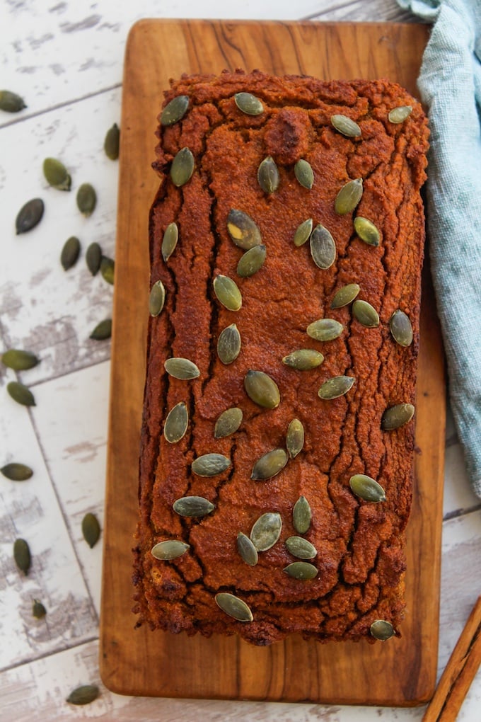 Paleo Pumpkin Bread topped with pepitas on a cutting board