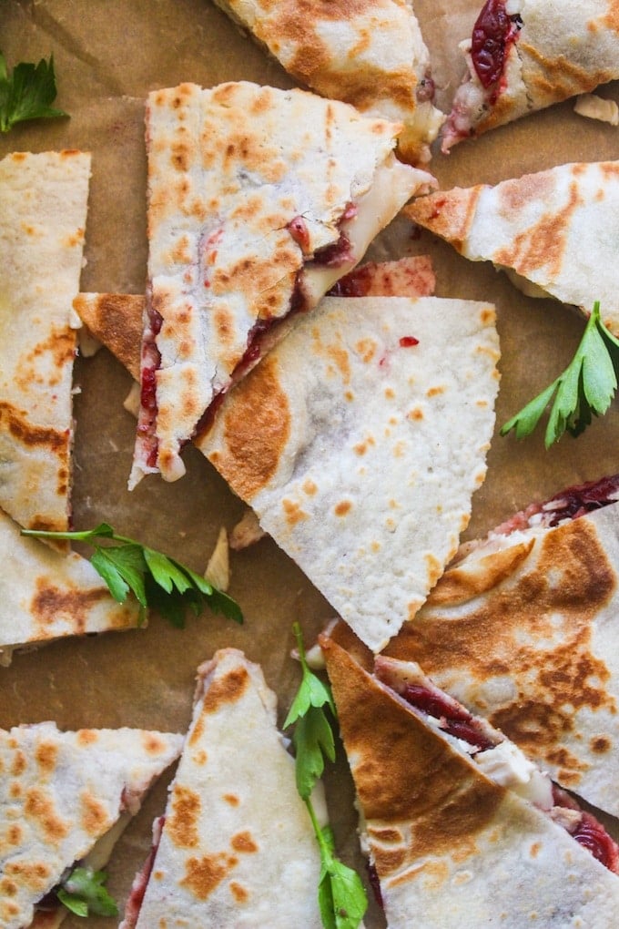 Turkey, cranberry, and brie quesadilla cut into triangle wedges in a pile with fresh parsley 