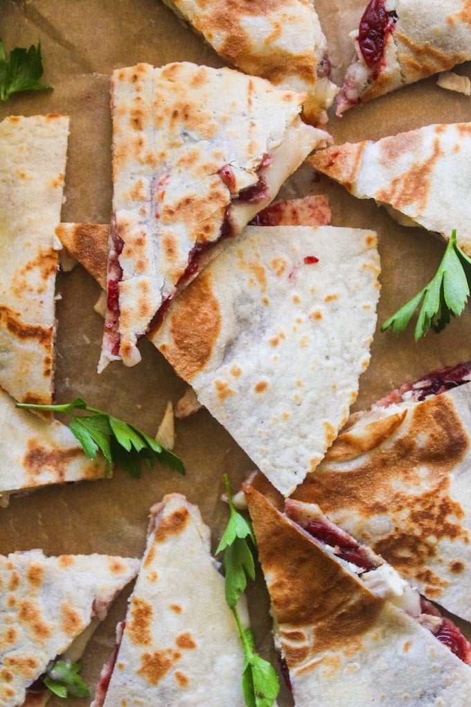 Turkey, cranberry, and brie quesadilla cut into triangle wedges in a pile with fresh parsley