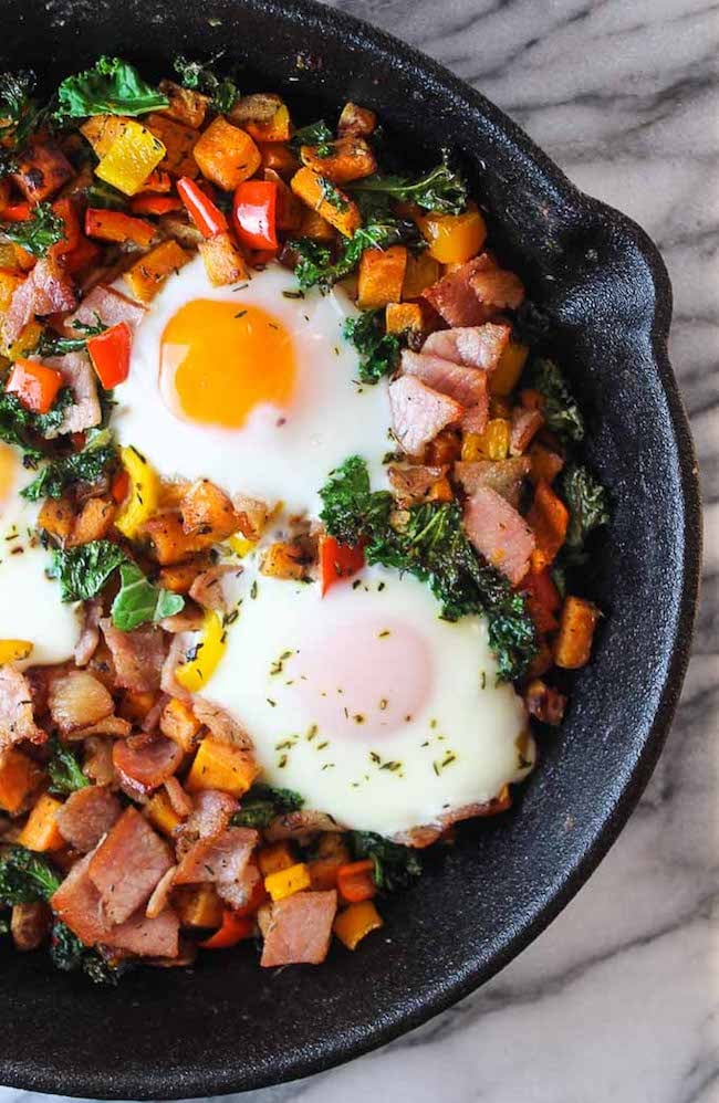 Bacon Kale & Sweet Potato Hash in a skillet with runny eggs on top