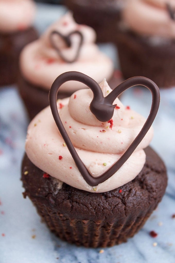 chocolate cupcake with strawberry frosting and chocolate heart on top