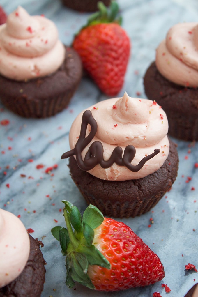 Paleo Chocolate Cupcakes with Strawberry Buttercream with melted chocolate piped into the word 'love' as a frosting decoration