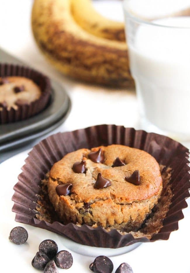 almond butter blender muffin topped with chocolate chips next to a glass of almond milk