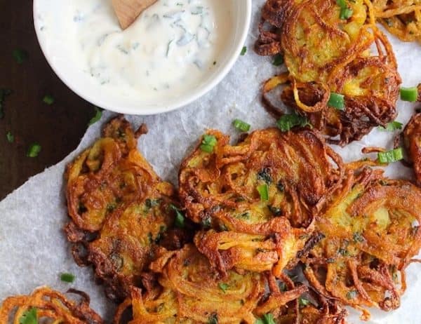 crispy onion bhajis on baking paper with a yoghurt dip