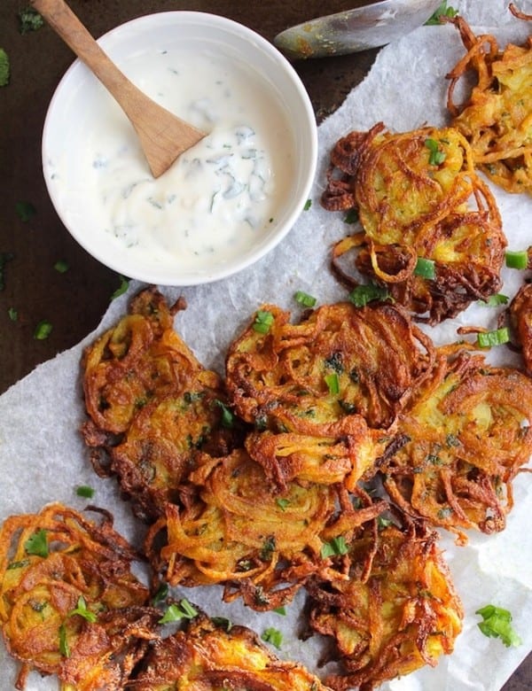crispy onion bhajis on baking paper with a yoghurt dip