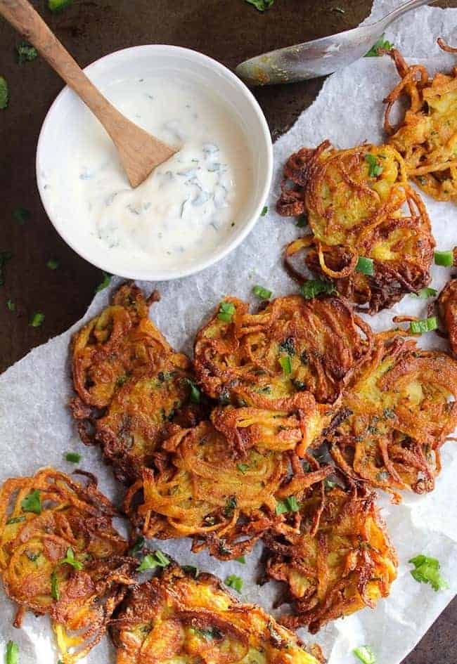 crispy onion bhajis on baking paper with a yoghurt dip