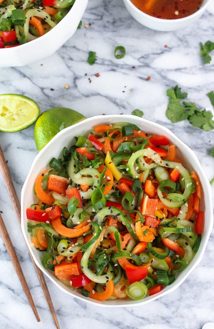 Asian Cucumber Sesame Salad in a bowl surrounded by cilantro and limes