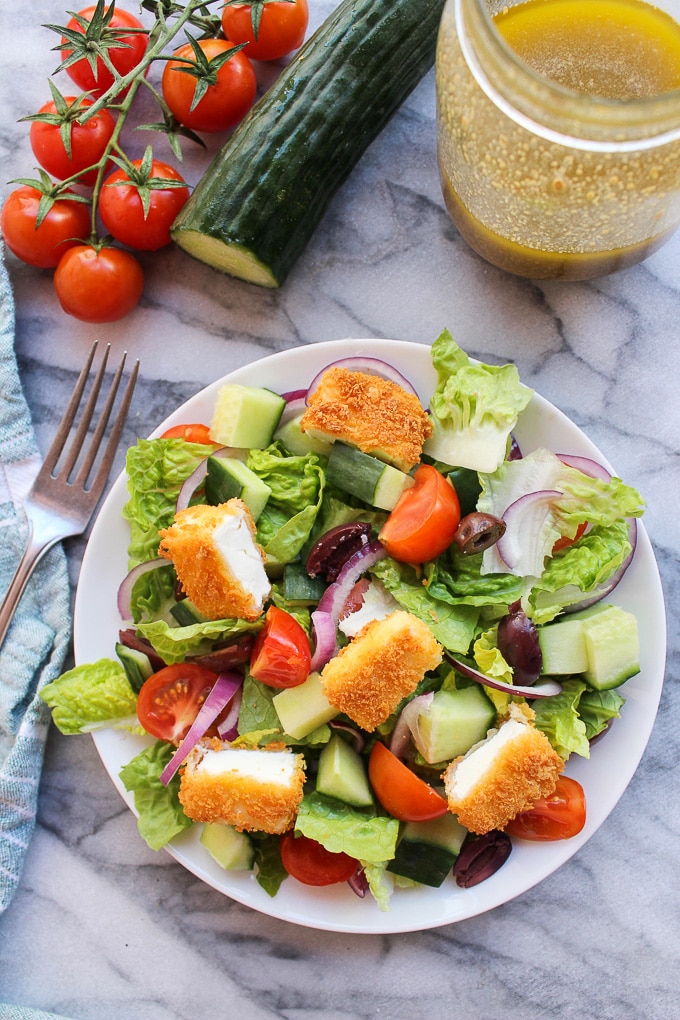 Crunchy Greek Salad topped with crispy fried feta coated in gluten free bread crumbs and dressed in a delicious red wine, lemon, and garlic herb vinaigrette 