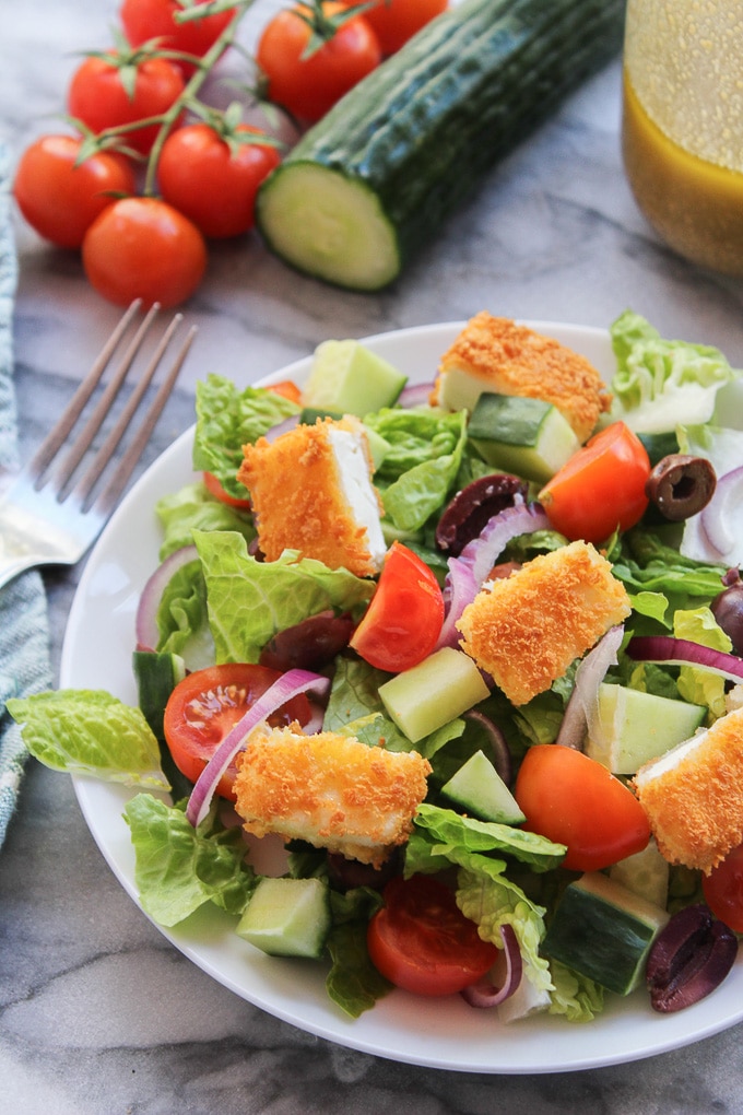 Crunchy Greek Salad topped with crispy fried feta coated in gluten free bread crumbs and dressed in a delicious red wine, lemon, and garlic herb vinaigrette 