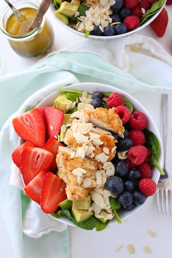 Easy mixed berry spinach salad with avocado, pan fried chicken,and flaked almonds dressed in a simple, honey poppy seed dressing!