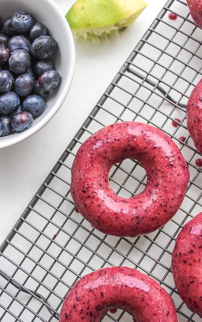 a baked vegan donut with a blueberry glaze on a cooling rack