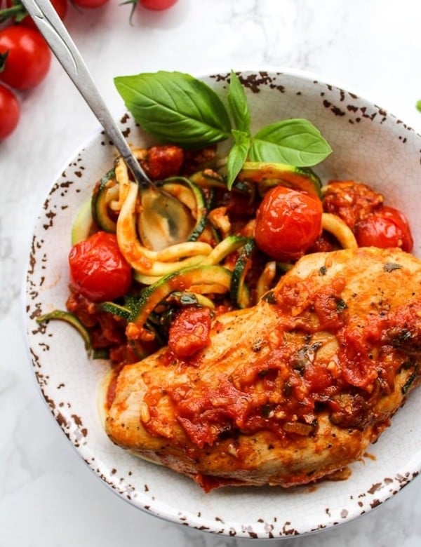 Tomato Basil Garlic Chicken over zucchini noodles in a bowl garnished with basil