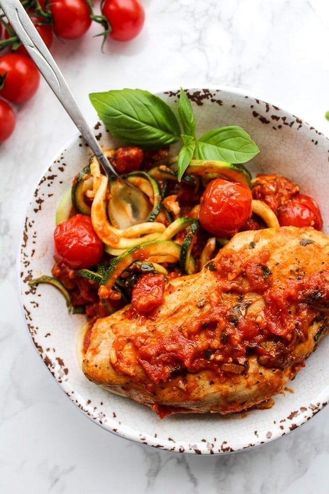 Tomato Basil Garlic Chicken over zucchini noodles in a bowl garnished with basil