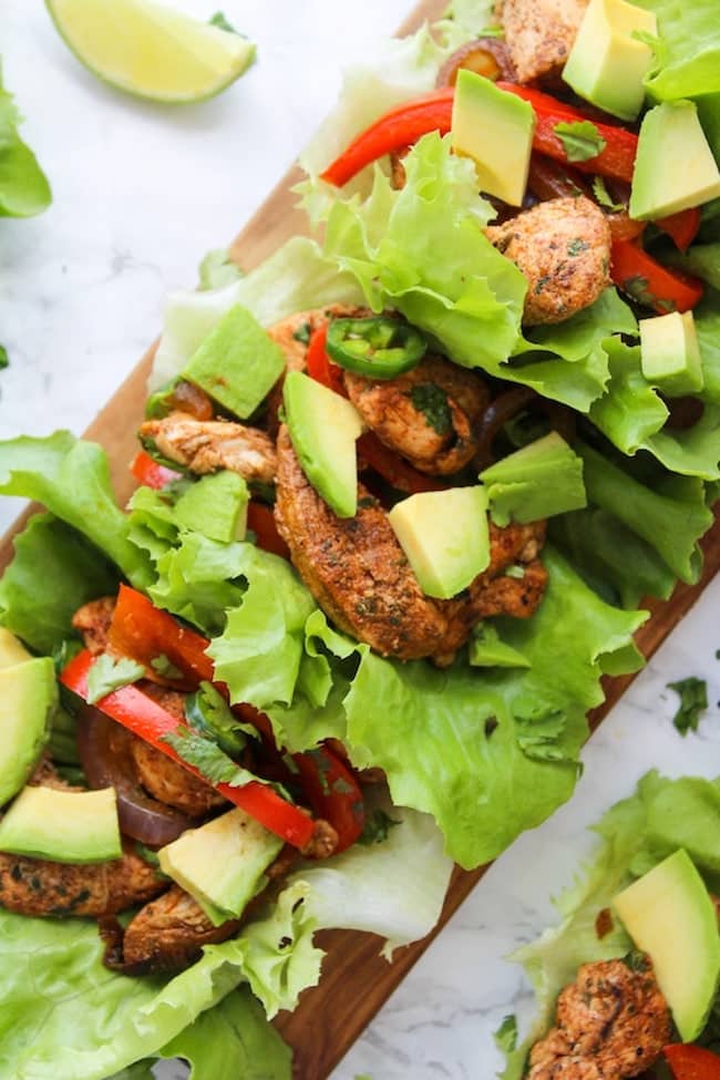 Easy Chicken Fajitas Lettuce Wraps with sautéed onions & peppers, seasoned chicken and topped with diced avocados 