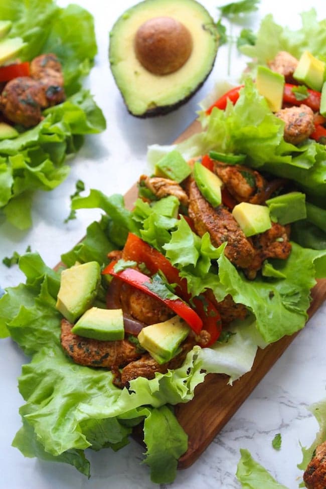 Easy Chicken Fajitas Lettuce Wraps with sautéed onions & peppers, seasoned chicken and topped with diced avocados 