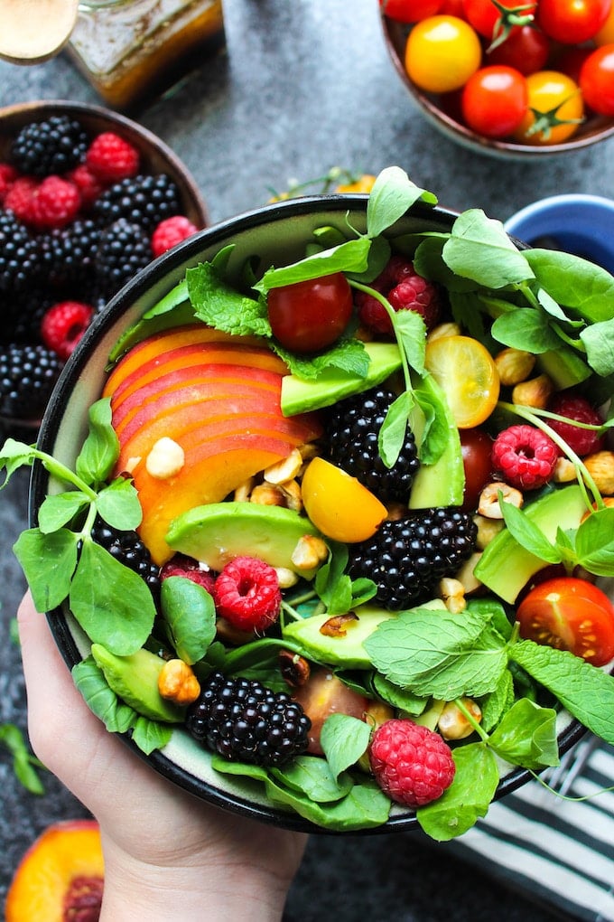 fruit and nut summer salad in a bowl topped with berries and avocado