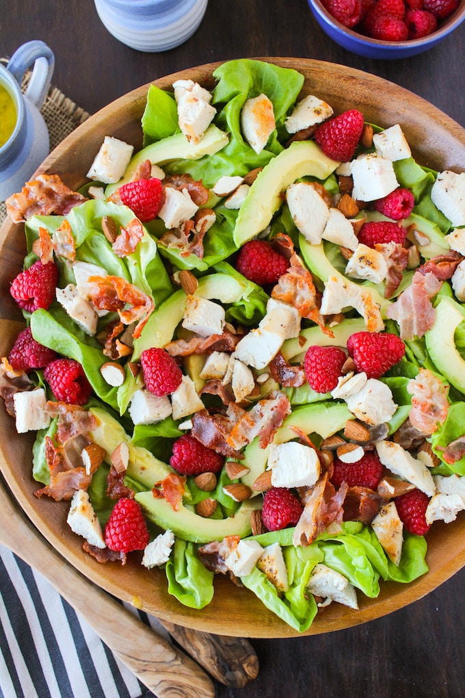 chicken & raspberry salad with sliced avocado, crispy pancetta, and a handful of almonds in a salad bowl