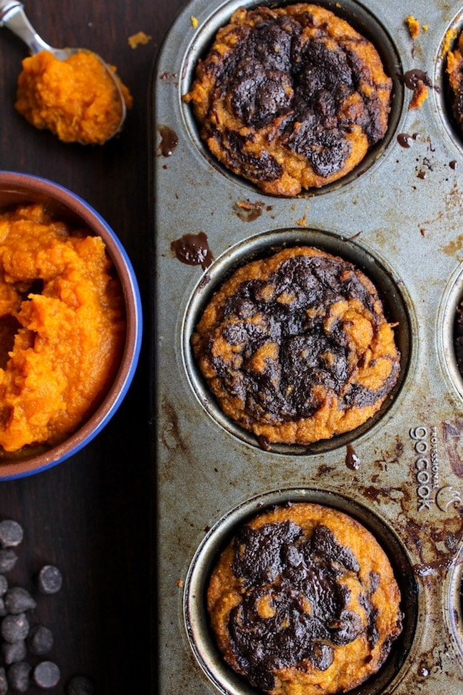 Paleo Pumpkin Muffins in a muffin tin surrounded by pumpkin puree