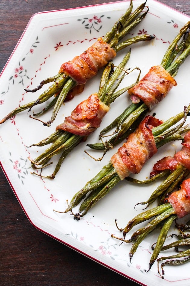 baked green beans wrapped in bacon and coated in a honey mustard sauce on a serving platter