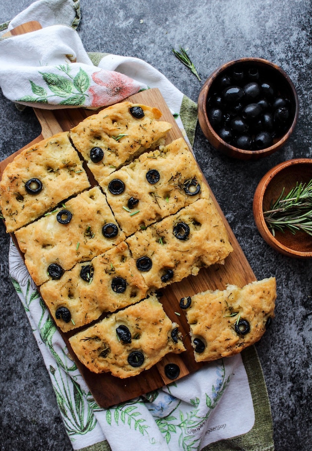 Gluten Free Focaccia Flatbread topped with sliced black olives and fresh rosemary. Made Vegan with aquafaba instead of eggs