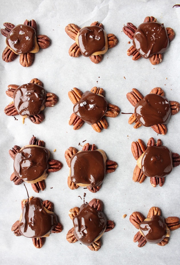 Vegan Chocolate Caramel Turtle Clusters - a five minute vegan caramel sauce drizzled over, crunchy toasted pecans and topped with dark chocolate shell. Only 7 ingredients! Paleo + Vegan 