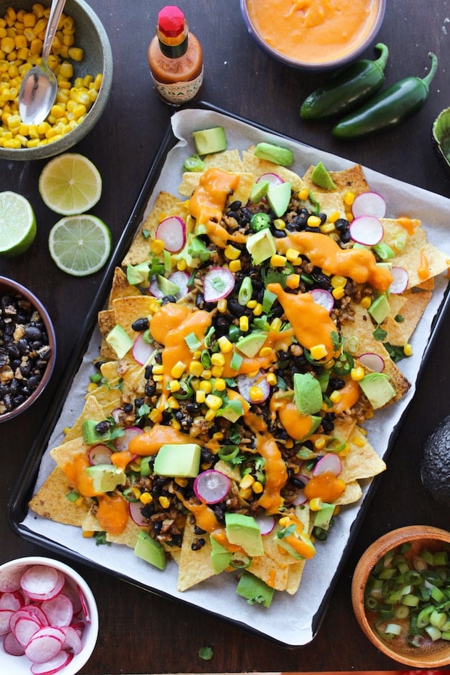 Easy, cheesy, plant based Vegan Nachos loaded with veggies, stretchy nacho cheese, and a black bean-walnut 'meat'. Gluten Free + Dairy Free