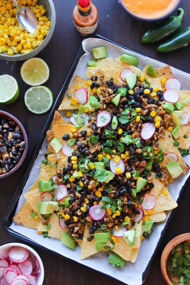 Easy, cheesy, plant based Vegan Nachos loaded with veggies, stretchy nacho cheese, and a black bean-walnut 'meat'. Gluten Free + Dairy Free