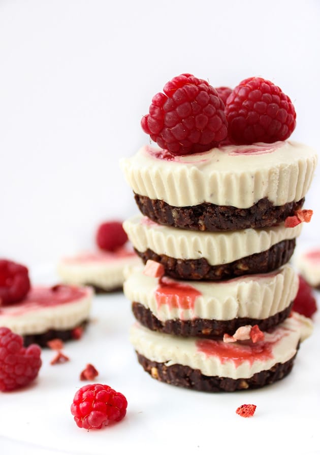a stack of  Raspberry Swirl Raw Cheesecake Cups with fresh raspberries on top