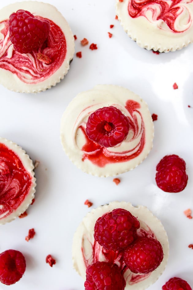 Raspberry Swirl Raw Cheesecake Cups with fresh raspberries all around