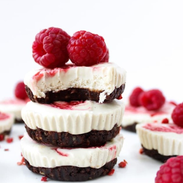 Raspberry Swirl Raw Cheesecake Cups stacked with raspberries on top