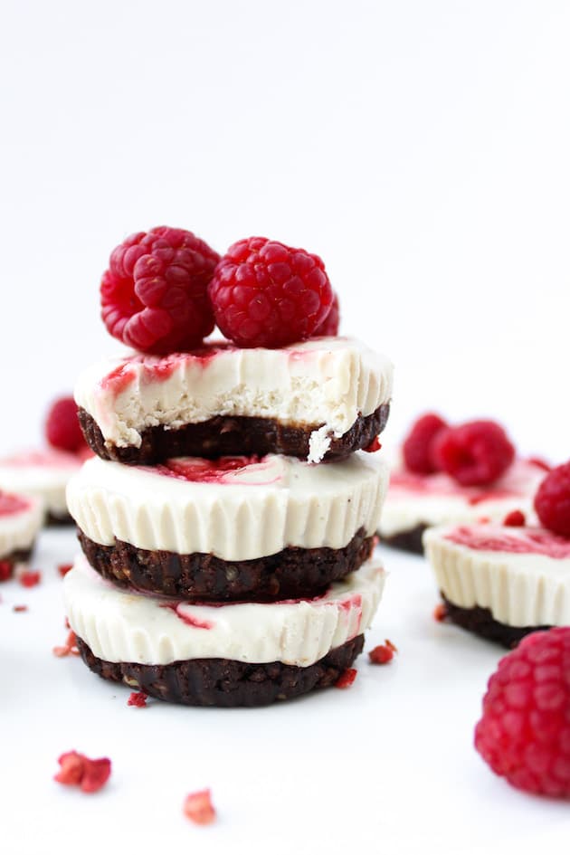 a stack of three Raspberry Swirl Raw Cheesecake Cups with a bite taken out of the top cup