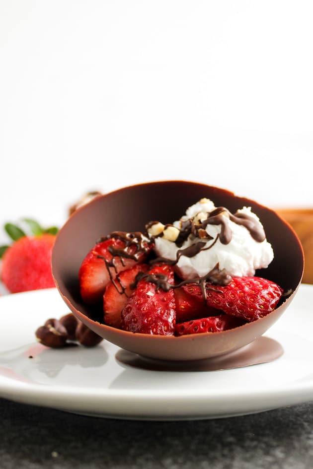 Homemade edible chocolate bowls filled with strawberries and coconut whipped cream