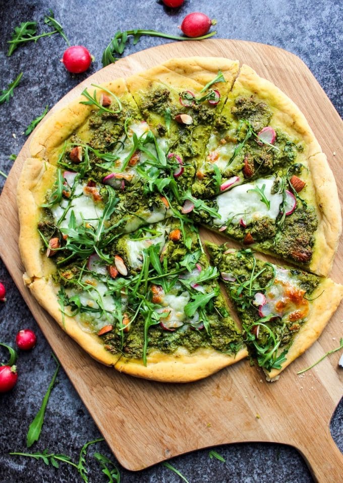 Super Green Kale Pesto Pizza topped with arugula, sliced radishes, chopped almonds and dollops of mozzarella. Gluten Free + Vegetarian 