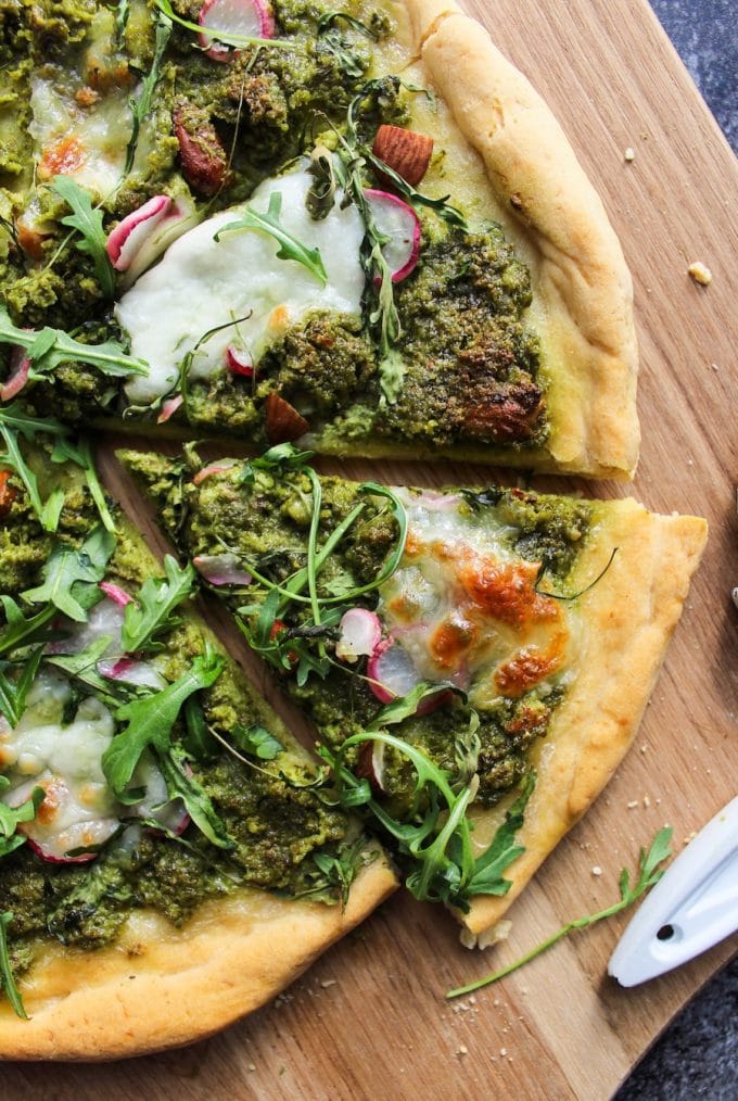 Super Green Kale Pesto Pizza topped with arugula, sliced radishes, chopped almonds and dollops of mozzarella. Gluten Free + Vegetarian 