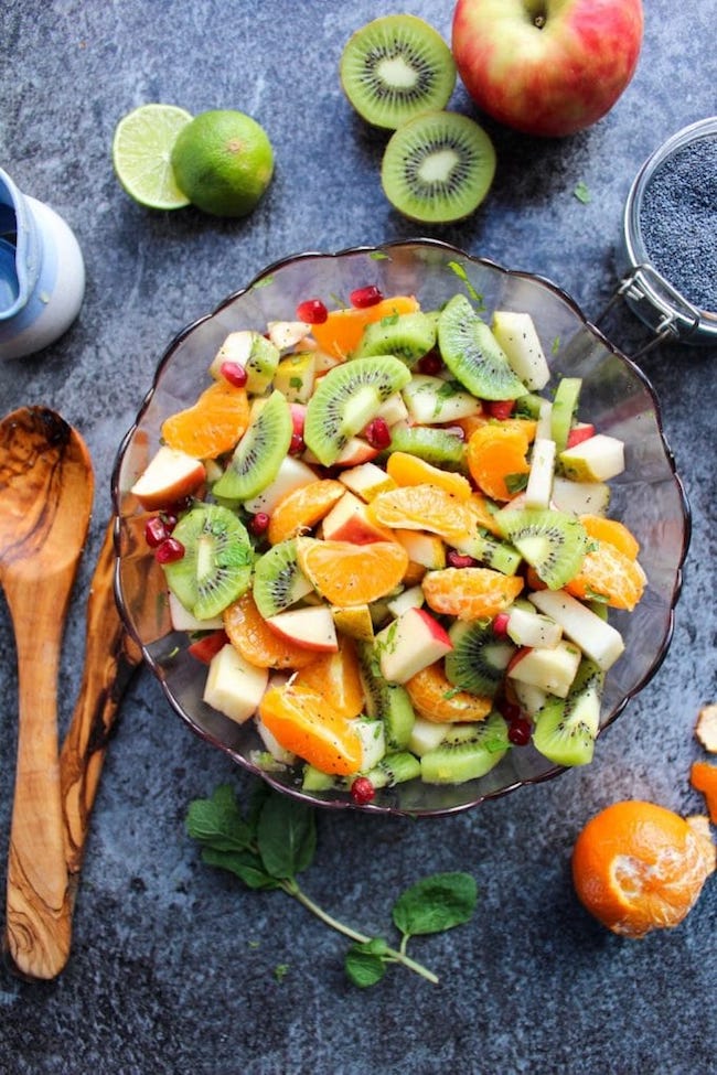 winter fruit salad in a salad bowl surrounded by fruit