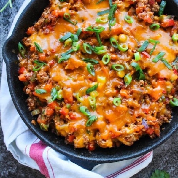 one pot taco skillet in a cast iron skillet topped with green onions and cheese