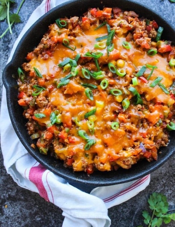 one pot taco skillet in a cast iron skillet topped with green onions and cheese