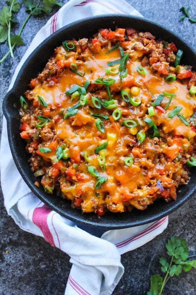 one pot taco skillet in a cast iron skillet topped with green onions and cheese