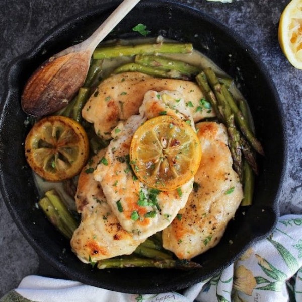 One Pan Lemon Chicken in a cast iron skillet topped with grilled lemons and parsley