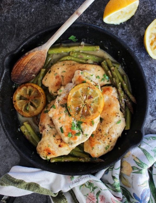 One Pan Lemon Chicken in a cast iron skillet topped with grilled lemons and parsley