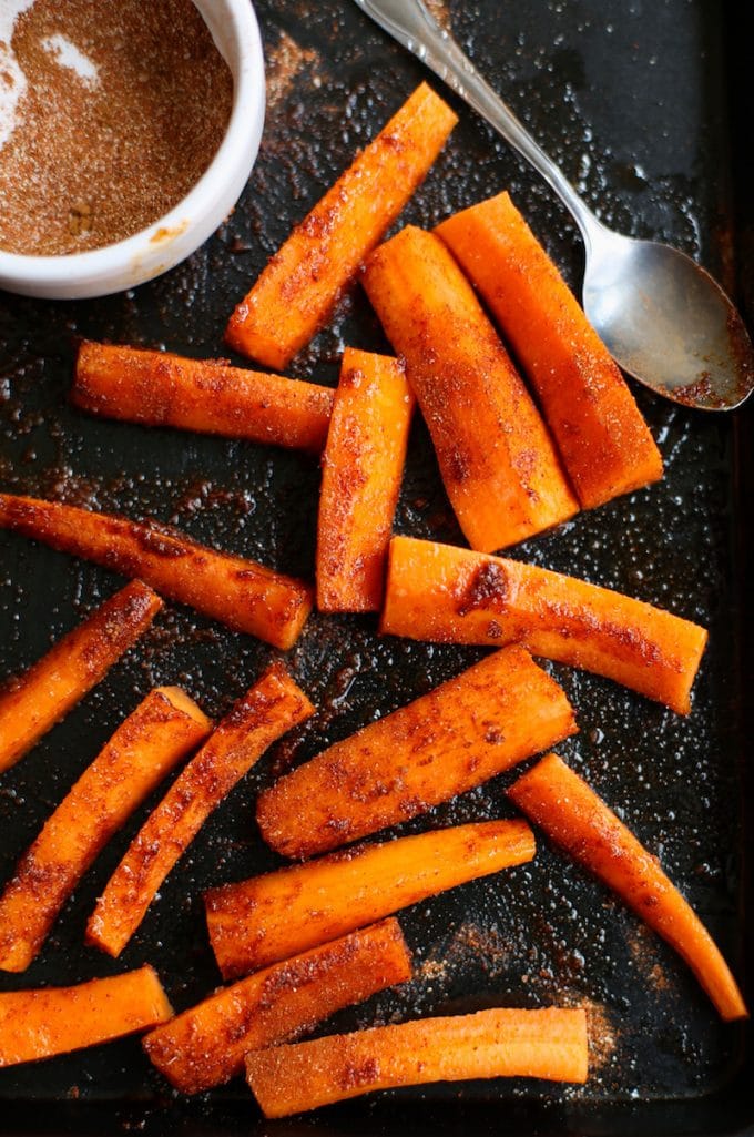 sliced carrots coated in spices and oil on a baking sheet